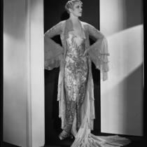 Peggy Hamilton modeling a Travis Banton hostess gown with beaded chiffon and gold lace, 1932