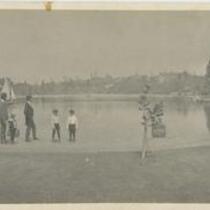 Panoramic of men and children gathered near water's edge at Westlake Park (MacArthur Park), Los Angeles